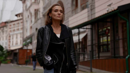 unhappy beautiful woman is walking in city in autumn day, wearing casual street style clothes