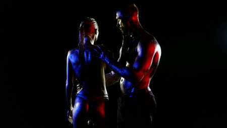 preliminary caress of loving pair in darkness with art light, bodies are covered shiny oilの写真素材