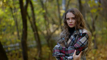 lonely and scared lady is standing alone in forest in autumn day