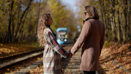 man and woman breaking up on tram rails in autumn day, walking to different sides