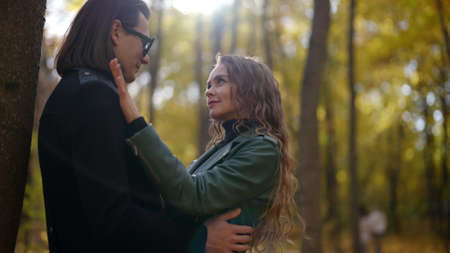 happy loving man and woman in autumn park, man is hugging his beloved girlfriendの写真素材