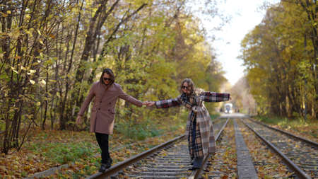 happy lovers are walking over old abandoned railway in autumn day, having funの写真素材