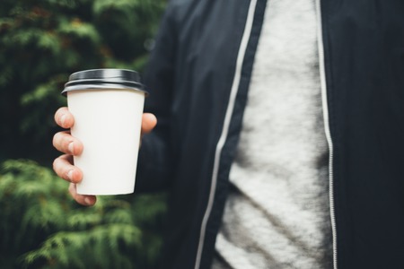 Young man holds a cup of coffee in his hands