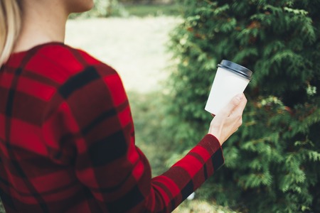 A young beautiful girl holds a cup of coffee in handsの写真素材