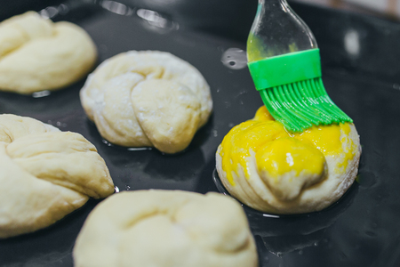 Greasing round dough close up. Round dough for a fancy cake greasing by green brush.の写真素材
