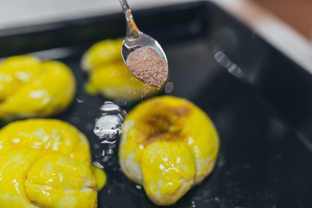 Woman sprinkling sweet rolls with cinnamon on slate plate in the kitchenの写真素材