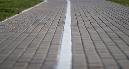 A road in the city laid out of paving slabs with a marked dividing stripの写真素材