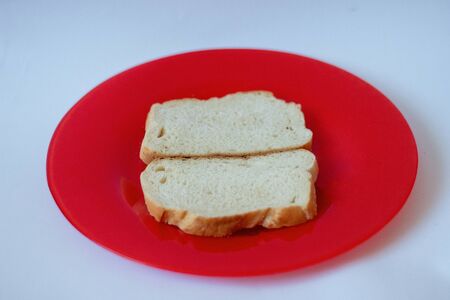 A loaf of bread lies on a red plate on a white background