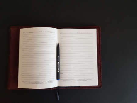 Grodno, Belarus-11.07.2020: Notepad and pen on a black isolated backgroundのeditorial素材
