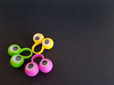Speech therapy toys eyes on fingers on a black isolated background