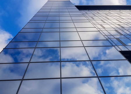 View of a modern glass skyscraper. Reflection of a cloudy blue sky in a glass skyscraperの写真素材