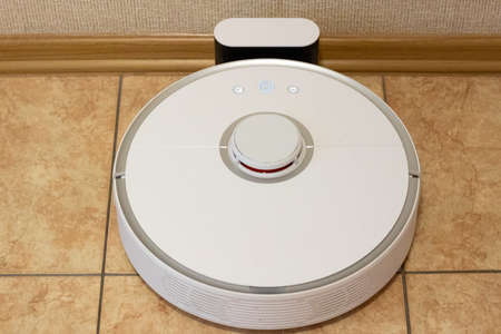 Robot vacuum cleaner on the charging dock after the finished cleaning of the room. Modern electronic...