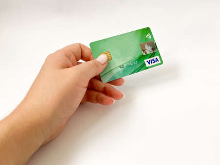 Grodno, Belarus - 07.21.2021: A Visa bank card is held in the hand on a white isolated background. Visa card close-upのeditorial素材
