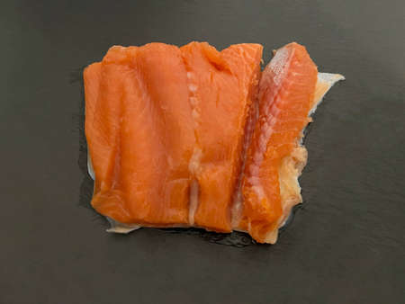 A piece of red lightly salted trout lies on a blackboard