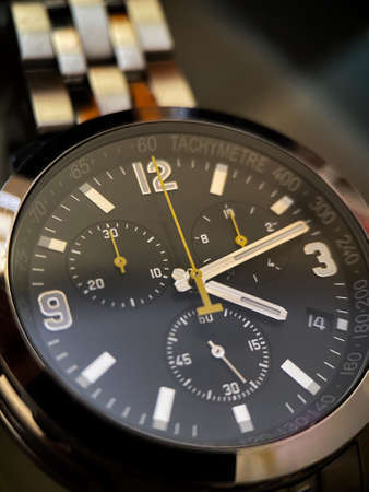 Luxury stainless steel watch with chronograph, black dial and metal bracelet close-up....