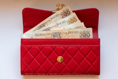 A red leather money wallet with 200 zloty bills in close-up on a white isolated background. Payment...