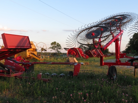 Rotors on new bright red hay raking equipment and sky and landscape behind  At sunset near Clarkson, Kentucky のeditorial素材