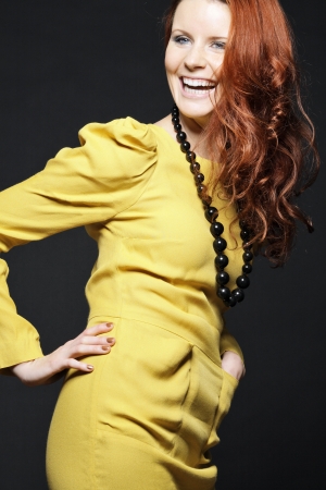 Beautiful young woman with curly hair posing in yellow dress.の写真素材