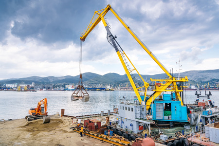 NOVOROSSIYSK, RUSSIA - JULY 12, 2016: Construction works in port. The excavator works for piers.