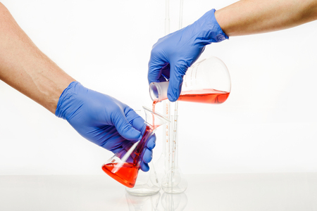 Carrying out an experiment in scientific chemical laboratory. Employees of laboratory conduct a research. Hands keep medical flasks in blue medical gloves.の写真素材