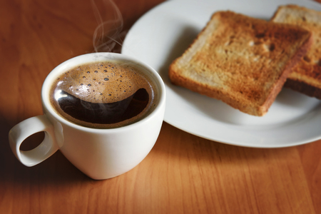 Hot black coffee in a white cup and fresh toast on a white plate. Morning breakfast.の写真素材