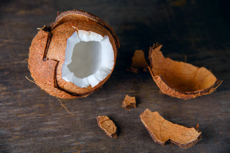 Broken coconut with pieces of skin on a wooden table, space for text, rustic tropical style.の写真素材