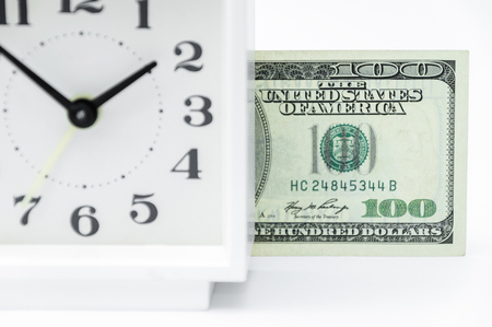 Financial concept of investments of money. Indistinct hours in the foreground and a banknote hundred dollars on a background.の写真素材