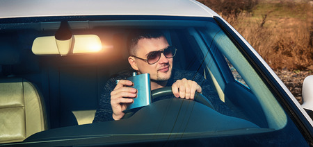 Man drink in car. Portrait driver in car with flask alcohol.の写真素材