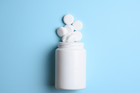 Pharmaceutical medicine tablets, pills, capsules and drugs on a blue background in white plastic jarの写真素材
