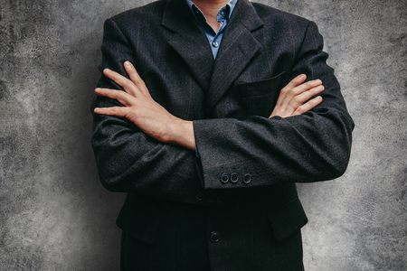Close up business man in a suit near the concrete wall. Man with crossed armsの写真素材