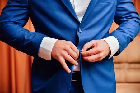 Man fastens a button on his jacket. Male arm and finger close up