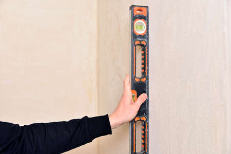 Worker Hand holds spirit level. Check the inclination of the wall with building level