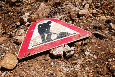 The road sign repair work lies on the ground. Old beaten and scratched road sign.の写真素材