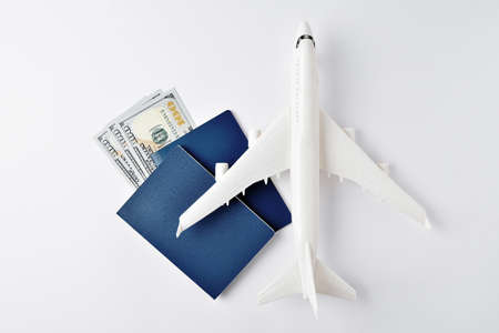 Travel concept, toy airplane with money and passports on a white background with copy space.