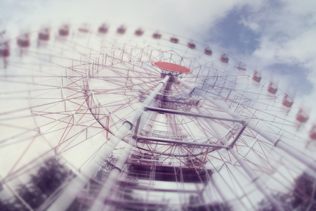 In amusement park, the Ferris wheel is spinning, blurry in motion, toned.の写真素材