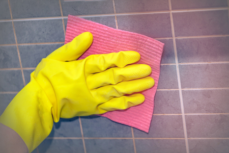 Hand in glove, washing wall from tiles in the kitchen or in the bath, toned.の写真素材