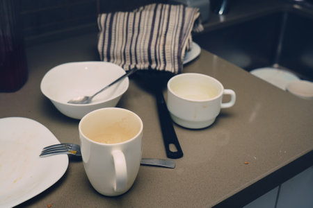 Many different dirty cups and plates on kitchen table near washbasin. Household concept.の写真素材