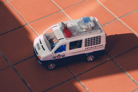 Old plastic toy police car with broken flash siren on tiling floor close up.の写真素材