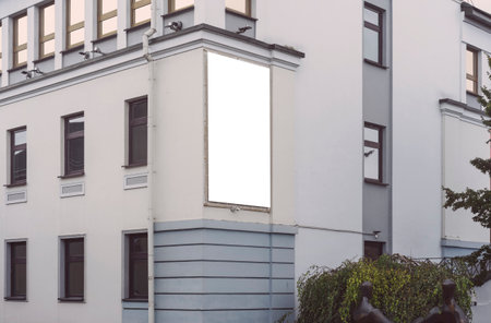 Vertical commercial poster with white blank space mounted on wall of urban building for advertising and promotionの写真素材