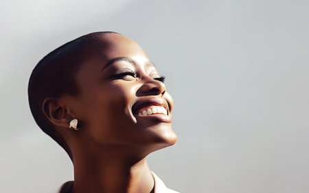 Happy smiling face of beauty afro lady model with dark skin and short hairstyle. Fashion posing in studio. Cancer and healthcare concept.の素材