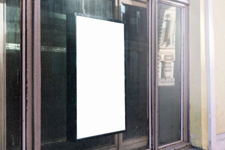 Vertical blank advertisement board on dusty storefront window in urban setting. Reflective glass surface shows city life, ideal for marketing mockup and urban design presentation.の写真素材