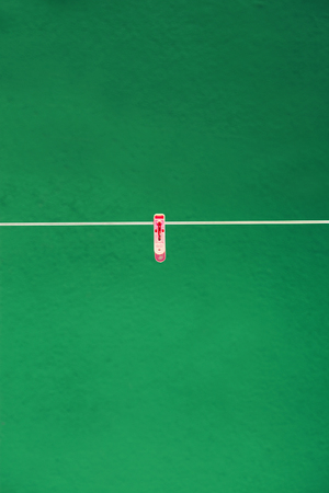 pink plastic clothespin front green wallの写真素材