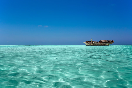 clear ocean maldives water and blue sky with abandoned boatの写真素材