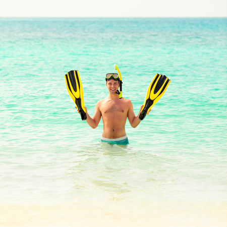 Man, relaxing on the white sand beach in the clear sea water, lying on the water with yellow and black flippers fins and mask. After snorkeling Maldives beach Youngの写真素材