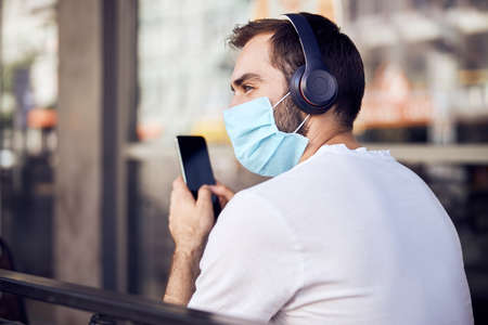 Man from behind  with phone in maskの写真素材