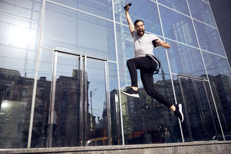 Man bouncing on the street with smartphoneの写真素材