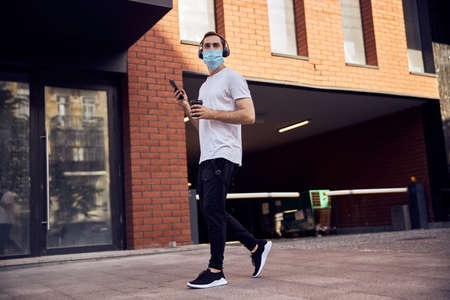 Man in mask is walking  with smartphoneの写真素材