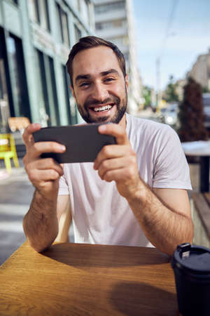 Masked man is sittiing  with smartphone in coffee room