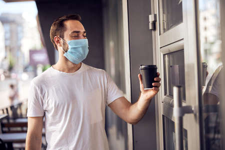 Masked man is sittiing  with smartphone in coffee room
