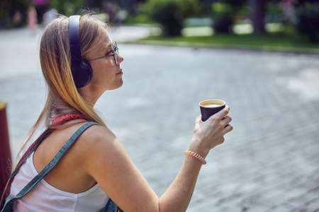 Waist up shot of beautiful red-haired girl with freckles in headphones who is listening to music ...